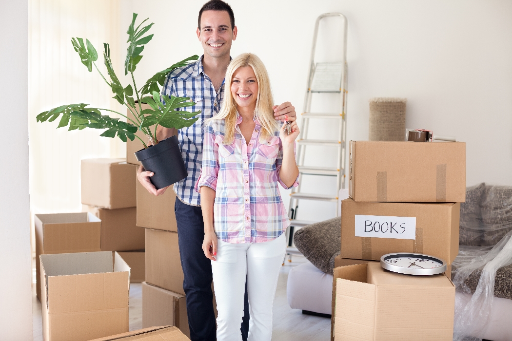 Young couple standing in new home. Represents relocation and unpacking.